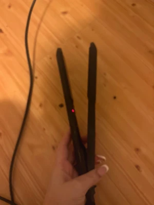 Svart plattång från Beautine - Säljer en svart plattång från Beautine med slimmad design och keramiska plattor. Plattången har en enkel on/off-knapp och lång sladd för smidig styling. Perfekt för att fixa håret snabbt och enkelt hemma.