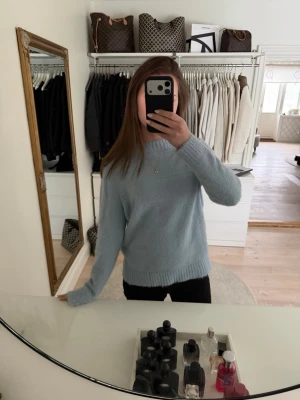 Ljusblå stickad tröja - Mysig ljusblå stickad tröja med rund halsringning och ribbade muddar. Den är köpt på club x-pris (en butik som inte finns längre) och har ett pyttelitet hål på framsidan. Skriv om du undrar över något 