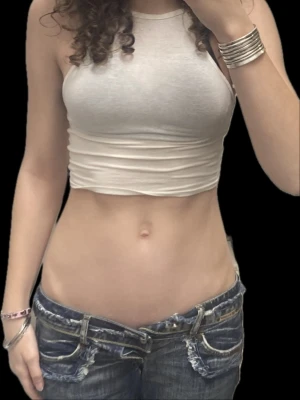 Vit croppad linnetopp - Snygg vit croppad linnetopp med hög hals och ärmlös design. Toppen är figurnära och har en enkel, stilren look som passar perfekt till jeans eller kjol. Perfekt för varma dagar eller som lager under en skjorta.