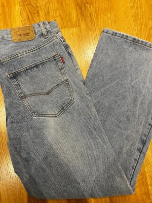 Levi's 501 straight jeans i ljusblå denim - Säljer ett par klassiska Levi's 501 jeans i ljusblått , med rak passform och fem fickor. Jeansen har den ikoniska läderpatchen bak och röd Levi's-tag vid bakfickan. Materialet är robust denim i bomull och färgen har en snygg tvättad look. SKICKAR SAMMA DAG 📦