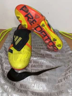 Adidas fotbollskor gula  - Säljer ett par Adidas Predator fotbollsskor i neon-gult med svarta och orange detaljer. Skorna har täckt snörning, svarta stripes och en cool orange sula med Predator-tryck. Perfekta för dig som vill sticka ut på planen.