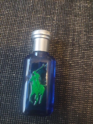 Blå parfymflaska med grön logga - Snygg parfym från Ralph Lauren i blå flaska med grön polospelare. Perfekt för dig som vill ha en stilren accessoar på hyllan. Volym och ingredienser syns ej på bilden.några sprut ba änvända 