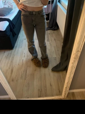 Gråa flared jeans med medel hög midja - Säljer ett par gråa jeans med medel hög midja och flared ben. Klassisk femficksmodell med knapp och dragkedja framtill. Jeansen har en enkel och clean look som passar till allt. Materialet är jeans i bomull och de sitter snyggt över höfterna. Jag är 1,63cm