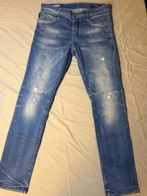Jack & Jones Tim vintage jeans ljusblå – Slim fit – 32/32 – Unika honeycombs - Sjukt unika Jack & Jones Tim slim jeans i ljusblå vintage-tvätt, storlek 32/32, i mycket bra skick. Har riktigt snygga honeycombs och slitningar som ger en autentisk vintage-look.  Perfekta för streetwear, Y2K, grisch och laidback stil. Ett par jeans som verkligen sticker ut.  Mått: Midja: 42 cm Längd: 104 cm  • Märke: Jack & Jones • Modell: Tim • Passform: Slim fit  Jack & Jones 3