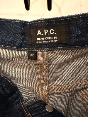 A.P.C. New Cure H jeans, mörkblå, stl 32 - Säljer ett par klassiska A.P.C. New Cure H jeans i mörkblå denim. Modellen har raka ben, fem fickor och knäppning med silverfärgade knappar. Snygg kontrastsöm och minimalistisk design. Perfekta för dig som gillar stilrena jeans med bra passform. Midja: 41cm Höft: ca 25 cm Benöppning: 19 cm Innerben: 70cm Felmarginal: +-1cm