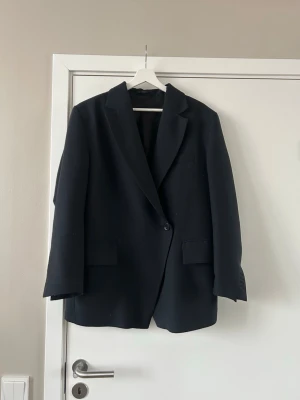 Svart kavaj från & Other Stories - Svart kavaj från & Other Stories med. Kavajen har två fickor framtill och är tillverkad i en mix av polyester, ull och elastan. 