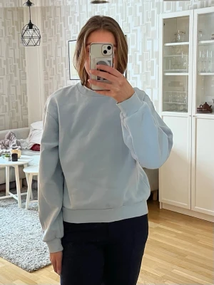 Ljusblå sweatshirt  - Säljer en stilren ljusblå sweatshirt från Gina Tricot med rund hals och ribbade muddar vid ärmslut och nederkant. Perfekt för chill dagar och enkel att matcha med jeans eller mjukisbyxor. Materialet är mjuk bomull som känns skönt mot huden.