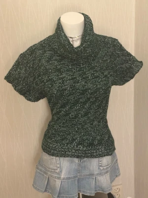 Grönmelerad stickad polotröja - En kortärmad polotröja i mörkgrönt med vita prickar. 30% ull  Made in italy