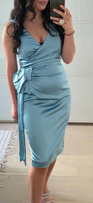 Blå festklänning  - Ljusblå satinklänning i storlek 38 säljs i fint begagnat skick. Endast använd 1 gång. Märket är Oasis. Behövs enbart en strykning. 