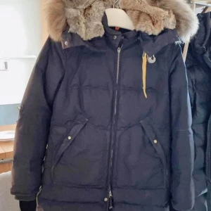 Mörkblå dunjacka från Parajumpers mycket bra skick M - Mörkblå Parajumpers jacka, inte mycket använd, mycket bra skick, finns bara en liten sliten detalj på vänstra sidan (visar på bilderna). Pälsen och luvan är avtagbara, jackan köptes för 9.999 kr. Storlek M. Kan mötas i centrala Stockholm.