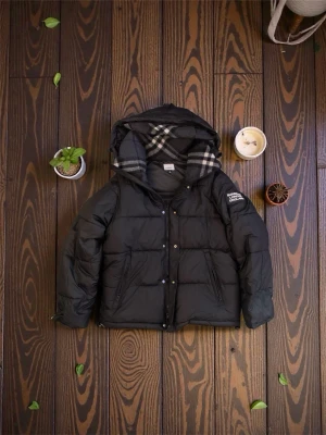 Svart pufferjacka från Burberry M - Svart pufferjacka från Burberry London England med stor patch på ärmen och klassiskt rutigt foder i huvan. Jackan har dragkedja, tryckknappar och två fickor framtill. Perfekt för kalla dagar och har en riktigt schysst streetstil.