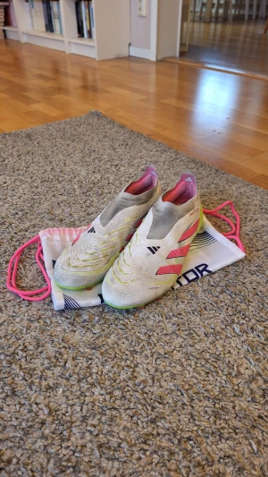 Adidas Predator Elite Laceless AG 'Celestial Victory' fotbollsskor  - Adidas Predator Elite Laceless AG 'Celestial Victory' fotbollsskor i storlek 45 1/3. Dem har lite smuts på sig då skorna har använts mycket(fråga gärna för fler bilder), men det påverkar inte skornas prestanda på träningar och matcher. Innersulan har lite defekter(bild 6). Dustbag ingår. Skick: 7.5/10