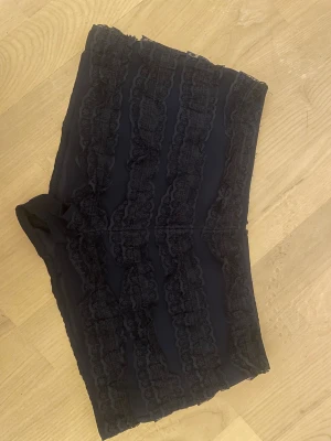 Mini spetsshorts - Mörkblå mini-shorts i spets. Dragkedja baktill. 