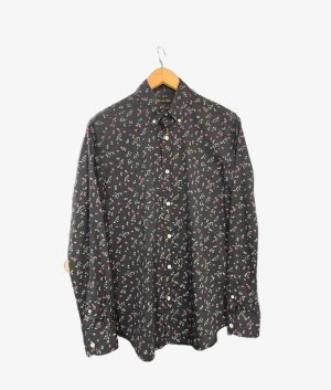 Blommig svart skjorta från Massimo Dutti - Svart skjorta från Massimo Dutti med små blommor i rött, blått och grönt. Skjortan har klassisk krage, vita knappar och långa ärmar med manschett. Tillverkad i mjuk bomull som känns skön mot huden. Perfekt för dig som gillar detaljer och mönster.