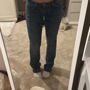 Blå bootcut jeans från Lee - Säljer ett par snygga blå jeans från Lee med klassisk bootcut-passform. Jeansen har fem fickor, normal midja och är tillverkade i slitstarkt denim. Färgen är mörkblå med lätt tvättade detaljer och Lee-logga på bakfickan. Perfekt för dig som gillar en tidlös jeansstil.