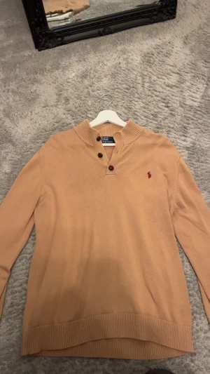 Beige stickad tröja Polo Ralph Lauren - Snygg beige stickad tröja från Polo Ralph Lauren i klassisk fit. Tröjan har ribbad krage. Står att den är XXL men passar S-M 