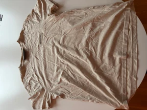 Beige t-shirt från Daily Performance - Säljer en beige t-shirt från Daily Performance med rund hals och korta ärmar. T-shirten har en enkel design med en diskret logotyp på bröstet. Perfekt för en chill och avslappnad stil. Materialet känns mjukt och skönt mot huden.