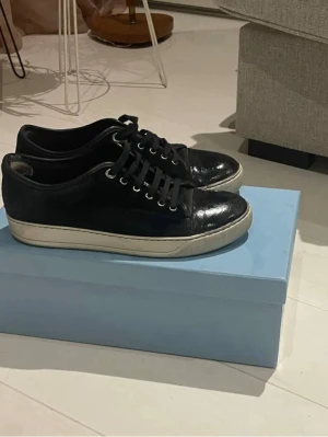Svarta sneakers från Lanvin i mocka - Stilrena svarta sneakers med vit sula och klassisk snörning. Perfekta för en clean och elegant look. Skorna är i bra skick och nyligen tvättade hos sneakers tvätten. Säljs utan originalkartong