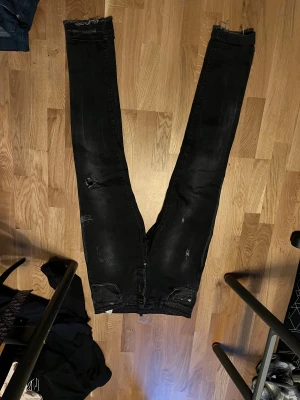 Svarta sklim fit jeans från Dsquared2 - Säljer ett par svarta skinny jeans från Dsquared2 i storlek 46. Jeansen har slitna detaljer, patchar med Dsquared2-logga på bakfickorna och smal passform. Materialet är klassisk jeans med stretch och de har dragkedja och knapp framtill.