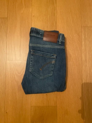 Dondup - Snygga blå jeans från Dondup med klassisk femficksdesign och brunt läderpatch bak i midjan. Jeansen har skinny passform och är tillverkade i mjukt jeansmaterial med lätt tvättade detaljer framtill och bak. Perfekta för dig som gillar en smal siluett.