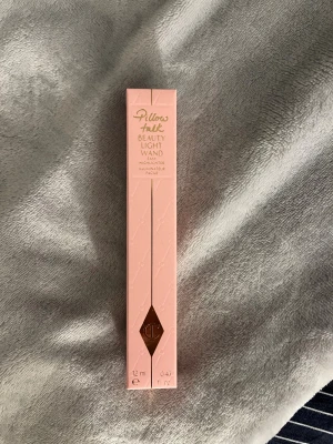 Charlotte Tilbury Pillow Talk Highlighter - Charlotte Tilbury Pillow Talk Beauty Light Wand i färgen Medium. Flytande highlighter i en rosa och guldig förpackning, 12 ml. Enkel att applicera med applikatorn för en glowig finish. Perfekt för att framhäva kindben och ge ansiktet lyster. Helt ny och oöppnad. 