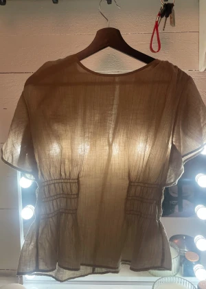 Bluss/festtop - Grön topp från H&M i storlek M. Tunt, stretchigt material som är formsytt och sitter fint på kroppen. Korta ärmar och bekväm passform – perfekt för både vardag och fest. I fint skick.