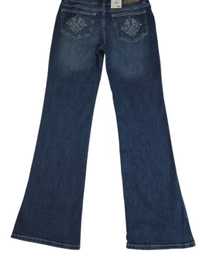 Blå bootcut jeans med broderade fickor - Snygga blå jeans med bootcut passform från Lager 157. Jeansen har broderade detaljer på bakfickorna och klassisk femficksdesign. Materialet är jeans och färgen är en mörkblå tvätt med lätt slitning framtill. Perfekt för dig som gillar en avslappnad och trendig stil.