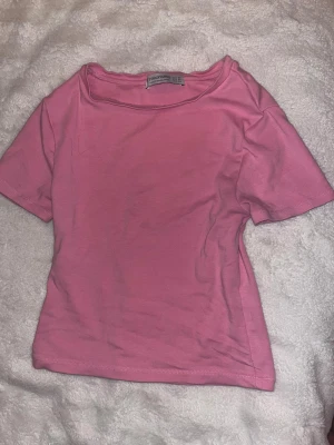 Rosa t-shirt från Stradivarius XS - Säljer en enkel och snygg rosa t-shirt från Stradivarius i storlek XS. T-shirten har korta ärmar och är gjord i mjuk bomull. Perfekt för dig som gillar färg och vill ha en basic topp i garderoben. Passar till jeans, kjol eller shorts.
