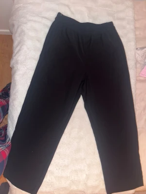 Svarta kostymbyxor från Lindex XS - Svarta kostymbyxor från Lindex, modell Bella. Byxorna har elastisk midja och är gjorda i ett mjukt material som känns skönt mot huden. Passformen är loose och de har raka ben. Perfekta för chill dagar eller när du vill vara extra bekväm.