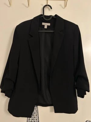 Svart kavaj med klassisk krage från H&M - Svart kavaj med klassisk krage och snyggt skräddad passform från H&M i storlek 34. 