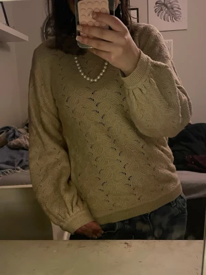 Beige stickad tröja från Minymo - Säljer en beige stickad tröja från Minymo i storlek 152. Tröjan har ett snyggt vågigt hålmönster, rund halsringning och ribbade muddar vid ärmslut och nederkant. Perfekt för lager på lager under hösten och vintern. Helt ny och oanvänd.