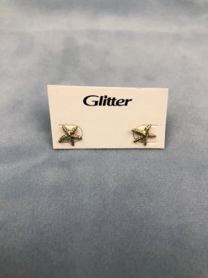 Sjösjärnor guldiga örhängen - Ett par guldiga örhängen från Glitter, formade som sjöstjärnor. 