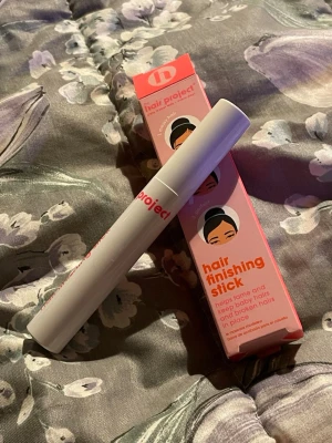 Hair Project hair finishing stick - Hair Project hair finishing stick i vit tub med rosa text. Perfekt för att tämja babyhår och småhår runt hårfästet. Kommer i en rosa förpackning med illustration och tydliga instruktioner. Enkel att använda och smidig att ha med sig i väskan.