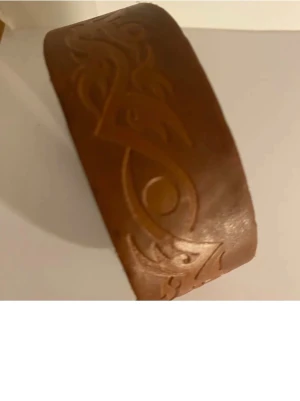 Brunt armband  med mönster  - Säljer en brun skinnväst med snyggt ingraverat mönster längs hela västen. Västen har tryckknappar för enkel stängning och en bred, klassisk form. Perfekt för dig som gillar westernstil eller vill sticka ut med en unik detalj. Fri frakt 