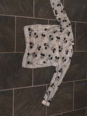 Vit långärmad Mickey Mouse t-shirt - Säljer en vit långärmad t-shirt från Disney med all-over print av Mickey Mouse i svart. T-shirten har rund hals och är gjord i mjukt bomullsmaterial. Perfekt för dig som gillar retro och tecknade motiv!(Det är ett sätt)