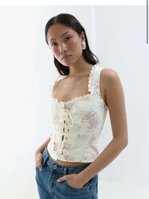 Gina Tricot Corset top - Säljer min helt oanvända corset top från Gina Tricot i färgen ”Vintage Flower”. Lappen är kvar och jag säljer pga att den inte passar mig. Super söt korsett topp med snörning där fram, fina detaljer vid urringningen och super sött blom mönster!🎀 Nypris 399,95 kr