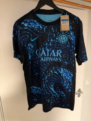 Nike Inter Milan fotbollströja blå/svart - Säljer en limited edition  Inter Milan fotbollströja från Nike med ett fett blått och svart mönster. Tröjan har Qatar Airways-logga på bröstet och Inter-emblem, samt eFootball-tryck på ryggen. Perfekt för dig som älskar fotboll och vill sticka ut på planen. 