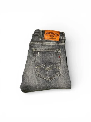 Replay Jondrill slim fit  jeans blå - Säljer ett par Replay Jondrill slim fit jeans i tvättad blå färg med slitningar och snygga detaljer. Klassisk femficksmodell med dragkedja och Replay-lapp bak i midjan. Jeansen har smal passform och är tillverkade i slitstarkt denimtyg. Måtten är 112 längd och 38 bredd och  Pris går att diskutera!