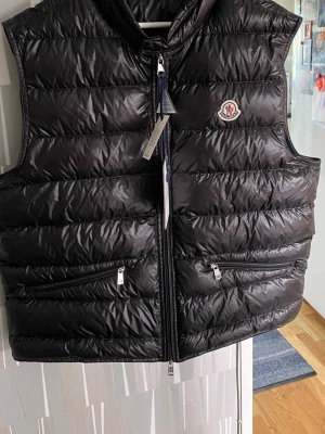Moncler gui väst - Svart moncler väst i storlek 5, passar L/XL. Som ny använd max 3 gånger. Påse med tags medföljer. Hör av dig om du har några funderingar. Mvh