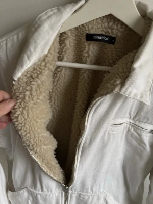 Vit teddyjacka från Gina Tricot - Säljer en vit teddyjacka från Gina Tricot i storlek M. Jackan har mjukt, fluffigt teddyfoder i beige, dragkedja framtill och praktiska fickor. Utsidan är i bomullstyg och jackan har en avslappnad passform med klassisk krage.