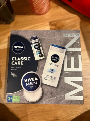 NIVEA Men Classic Care presentbox - Presentbox med NIVEA Men Sensitive duschgel 250 ml och NIVEA Men Creme 50 ml. Duschgelen är vit med blå detaljer och har bambuextrakt, medan krämen kommer i en rund burk med blå lock. Perfekt för ansikte, kropp och händer.