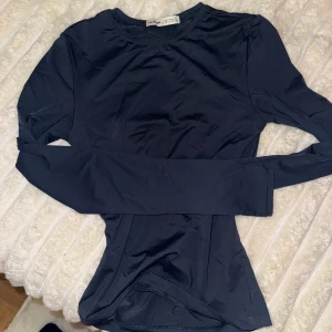 Mörkblå långärmad topp från Pull&Bear - Säljer en stilren mörkblå långärmad topp från Pull&Bear i storlek XS. Toppen har en rund halsringning och är figurnära i passformen. Materialet är mjukt och stretchigt, perfekt för att skapa en clean och enkel look.