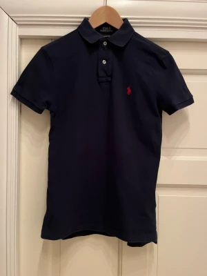 Mörkblå Ralph Lauren Piké - Snygg slim fit RL piké säljs. Mycket fint skick. Storlek xs. Mörkblå med röd logga. Original pris 1499kr Mitt pris 399kr