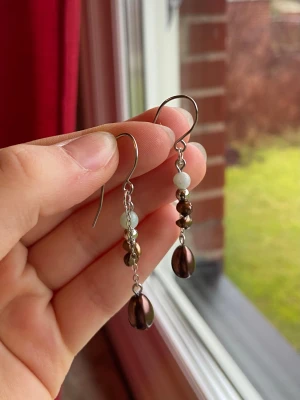 Hängande örhängen med pärlor - Snygga handgjorda örhängen med silverfärgad krok och kedja, dekorerade med bruna droppformade pärlor, små oregelbundna bruna pärlor och ljusblå runda pärlor. Perfekt för dig som gillar unika smycken med boho-vibe.