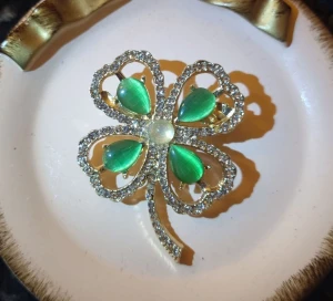 Fyrklöver brosch  - Elegant klöverbrosch dekorerad med pärlor och strass. Fyrklöver anses som en lyckosymbol.   Material : legering Färg : gyllene Mått 4 x 5 cm  Jag erbjuder presentinslagning. Bara säga till!