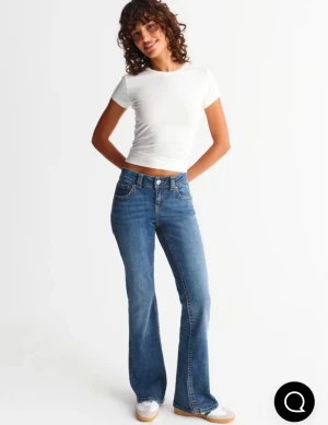 Gina Tricot bootcut jeans blå - Säljer ett par klassiska bootcut jeans i blå tvätt. Modellen har låg midja, fem fickor och snygga sömmar. Jeansen är tillverkade i slitstarkt denim och har en bootcut passform som ger en schysst siluett. Perfekt för dig som gillar retrovibbar och tidlös stil.