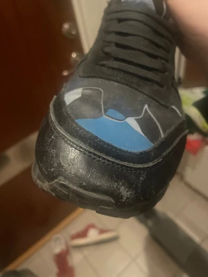 Valentino Rockrunner sneakers blå/svart - Säljer ett par Valentino Rockrunner sneakers med coolt blått och svart camouflage-mönster. Skorna har snörning, platt sula och detaljer i skinn och syntet. Perfekt för dig som vill sticka ut med ett unikt mönster och snygga färgkombinationer.