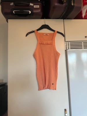 Ribbad persikofärgad linnetopp Odd Molly - Säljer en ribbad persikofärgad crop topp från Odd Molly. Toppen är ärmlös med breda axelband och har en söt volangdetalj framtill. Materialet är mjukt och stretchigt, perfekt för varma dagar. Liten metallogo nertill på framsidan. Storlek 4 som enligt deras storleksguide motsvarar en XL. Passar säkert M-XL, det beror på hur man vill att den ska sitta. Mycket fint skick, jag hittar inga synliga anmärkningar eller defekter. 