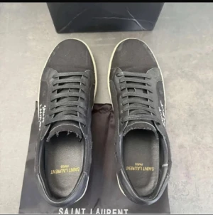 Saint Laurent sneakers - Säljer ett par svarta Saint Laurent sneakers med vita sulor och svart snörning, i nyskick. Skorna har den klassiska saint Laurent loggan på sidan och kommer med en svart dustbag. Dustbagen ingår i priset på 3000 kr  vilken deal! Perfekta skor för dig som vill ha både stil och kvalitet. Hör av dig vid intresse!
