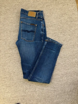 Blå skinny jeans från Nudie Jeans - Vi säljer nu ett par snygga blåa jeans från Nudie Jeans. Modellen har en smal-medium passform och raka ben. Jeansen är tillverkade i ett mjukt och behagligt denimtyg och har normal midja. Vi säljer dessa till ett kanonpris. Observera att jeansen har blivit lagade på Nudie Jeans butik i Göteborg men är nu som nya, i toppskick. Tveka inte på att höra av dig vid minsta lilla fråga! Priset kan diskuteras vid snabb och smidig affär. 😁😁